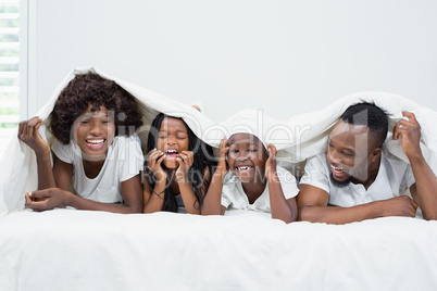 Happy parents and kids lying on bed