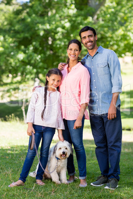 Portrait of happy family with their pet dog standing in park