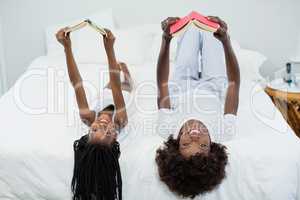 Mother and daughter reading novel in bedroom at home