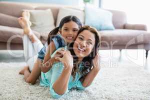 Portrait of happy mother and daughter lying on rug