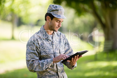 Soldier using digital tablet in park