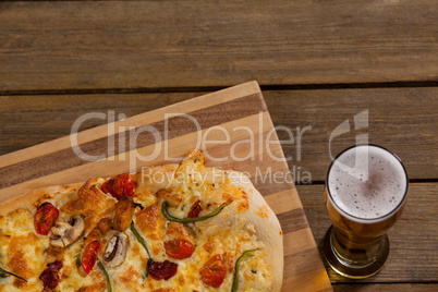 Delicious pizza served on wooden board with a glass of beer