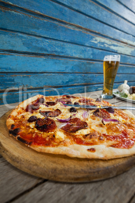 Italian pizza served with glass of beer on wooden plank