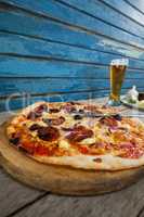 Italian pizza served with glass of beer on wooden plank