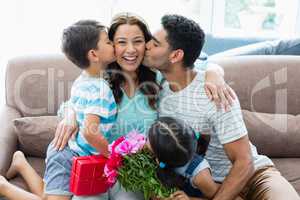 Woman receiving kiss from his husband and kids in living room