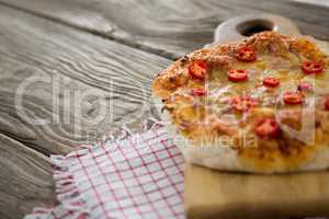 Pizza served on a chopping board with a cloth on a wooden plank
