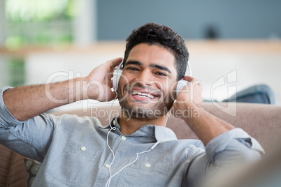 Man listening to music on headphones in living room at home