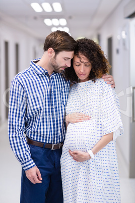 Man comforting pregnant woman in corridor