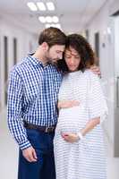 Man comforting pregnant woman in corridor