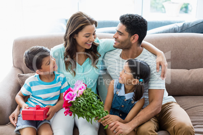 Parents and kids interacting on sofa with present in living room