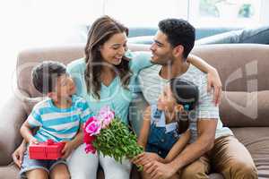 Parents and kids interacting on sofa with present in living room
