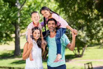Portrait of parents carrying their children on shoulder in park