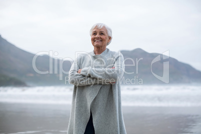 Senior woman standing with arms crossed on the beach