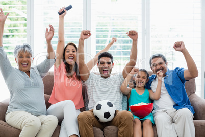 Happy multi-generation family watching soccer match on television in living room