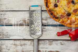 Italian pizza on wooden plank with red chili and grater