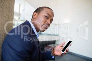 Worried businessman holding mobile phone