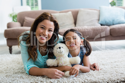 Portrait of happy mother and daughter lying on rug