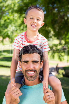 Portrait of father carrying his son on shoulders in the park