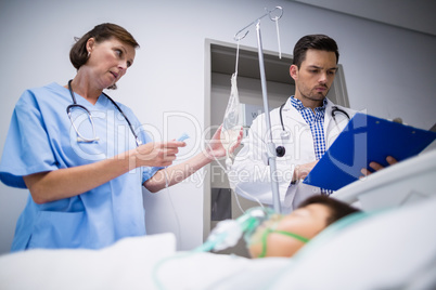 Doctors adjusting iv drip while patient lying on bed