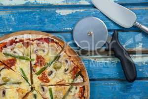 Delicious pizza served on pizza tray with cutter and knife on wooden plank