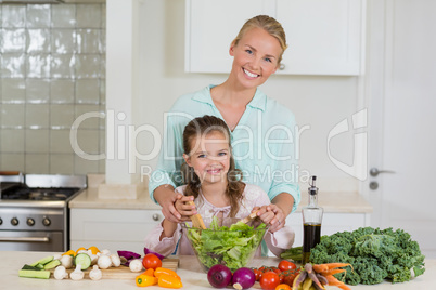 Mother and daughter preparing salad in kitchen