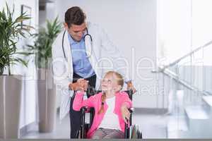 Doctor pushing girl in wheelchair