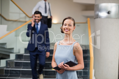 Cheerful businesswoman holding digital tablet at conference centre