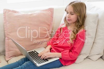 Girl using laptop on sofa in living room