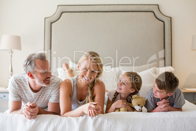 Parents with their kids lying on bed in bedroom