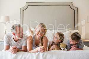 Parents with their kids lying on bed in bedroom