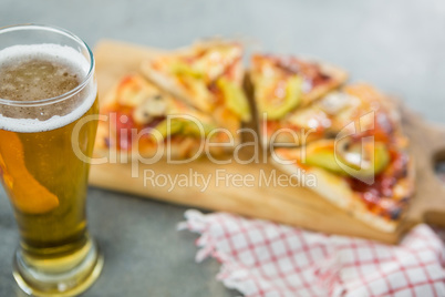 Glass of a beer with pieces of pizza in the background