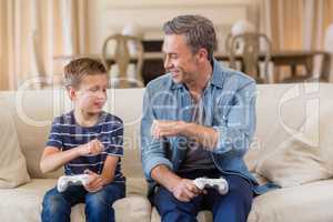 Father and son giving fist bump to each other while playing video game in living room