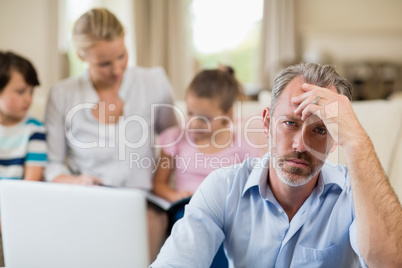 Tense man with hand on forehead sitting in living room