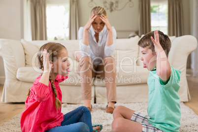 Upset woman sitting on sofa while siblings teasing each other