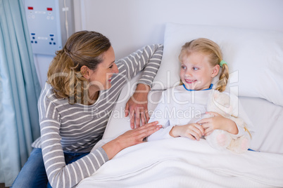Mother talking to daughter in hospital bed
