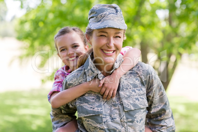 Female soldier giving a piggyback ride to her daughter in park