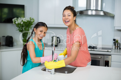 Mother assisting her daughter in cleaning vessel at home