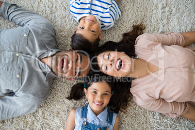 Portrait of happy parents and children lying on rug
