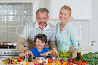 Smiling parents and son chopping vegetable in kitchen