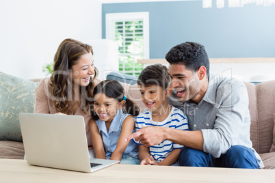 Parents and kids using laptop in living room