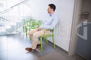 Man sitting on chair in hospital corridor