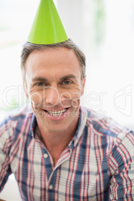 Smiling man with party hat at home