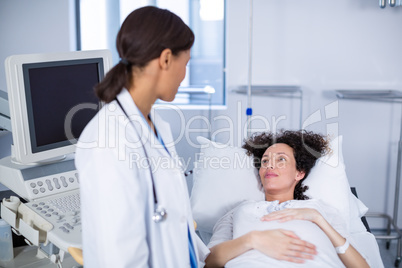Doctor interacting with pregnant woman while doing ultrasound scan