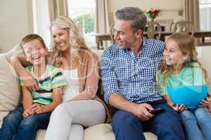 Parents and kids having fun while watching tv in living room