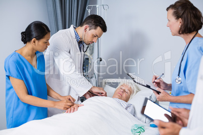 Doctors examining patient in ward