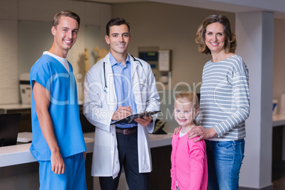 Portrait of doctors discussing medical report with mother and daughter