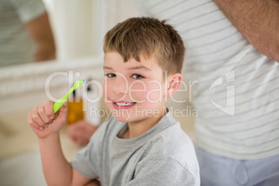 Portrait of boy brushing teeth in bathroom