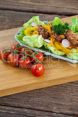 Vegetable salad and cherry tomato on wooden board