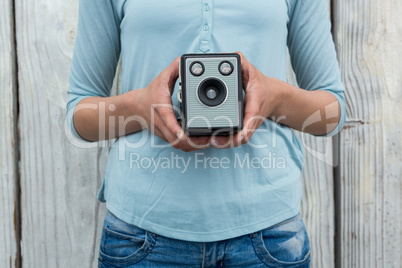 Mid section of female photographer holding old fashioned camera