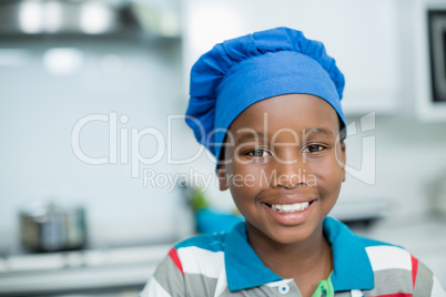 Smiling boy in chefs hat at home